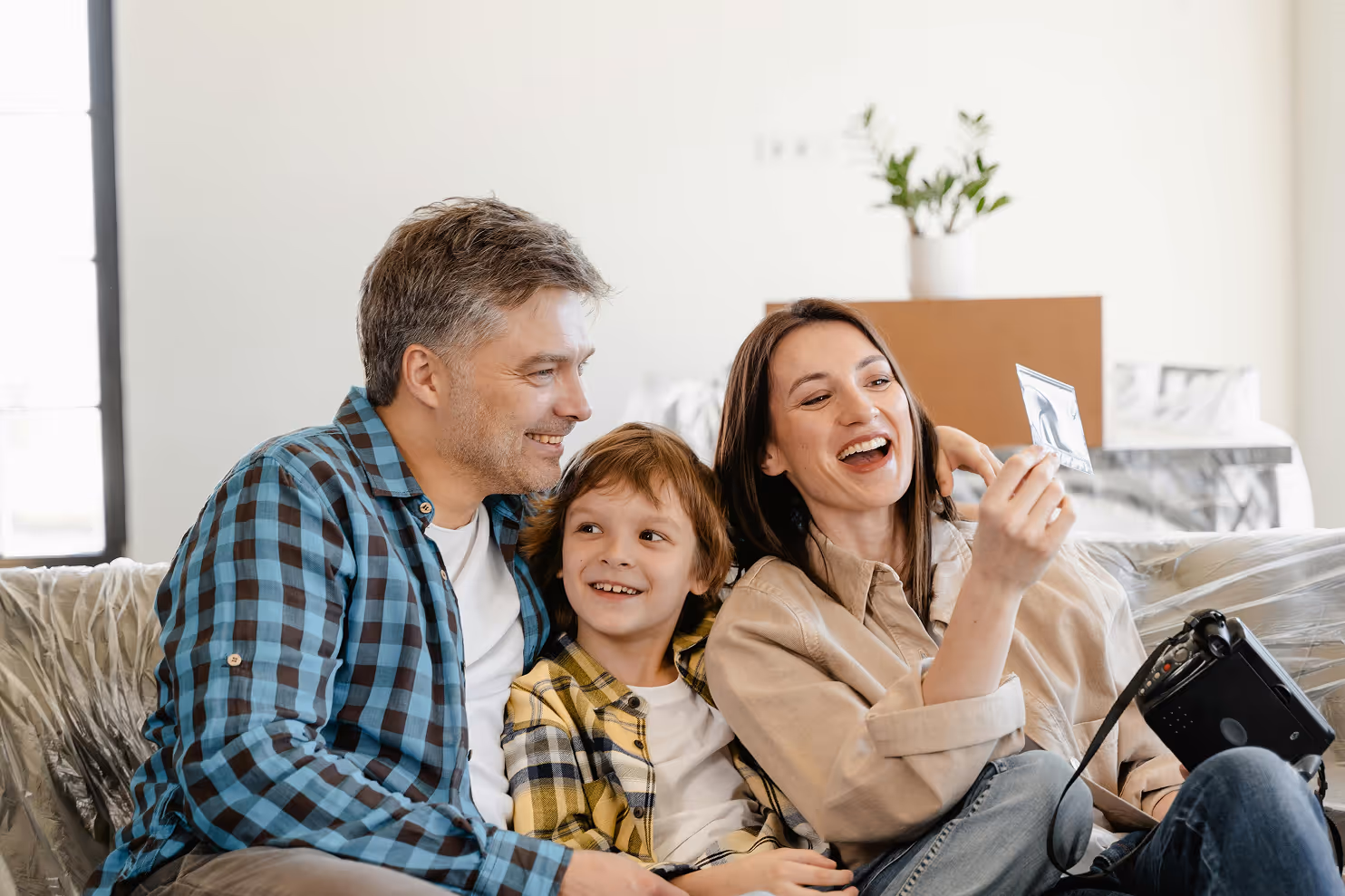 Junge Familie sitzt lachend auf dem Sofa