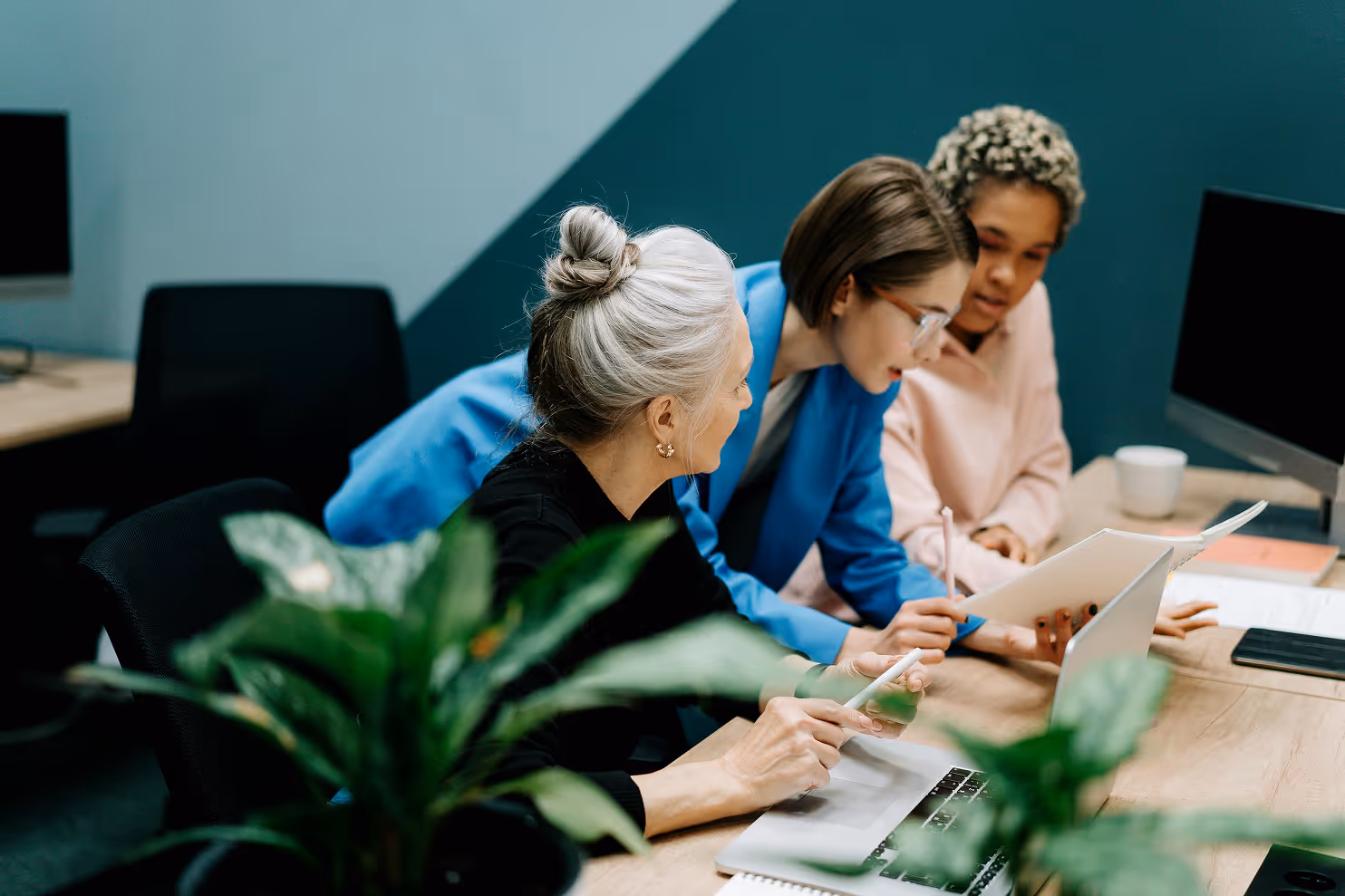 Drei Frauen sitzen in einem Büro und sehen sich Unterlagen an